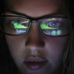 woman with computer screen reflecting in her glasses
